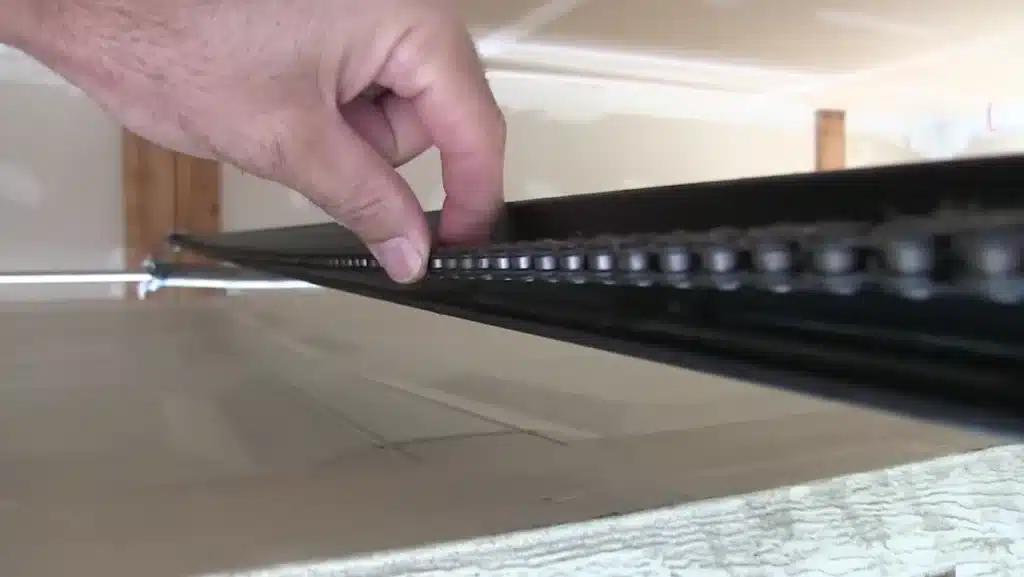 Sagging garage door opener chain showing excessive slack on the motor rail