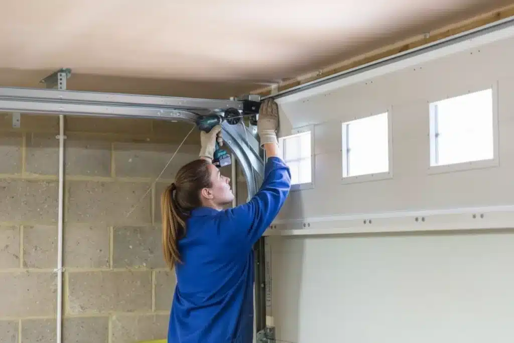 Close-up of a person inspecting garage door torsion springs and safety cables for wear and tear.