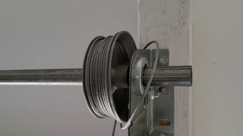 A tangled garage door wire resembling a "bird's nest" caught on the torsion spring drum, indicating it's off track.