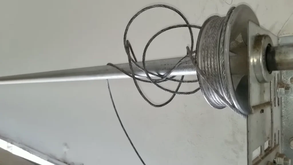 A garage door cable off track and tangled around the torsion drum after hitting an obstruction.